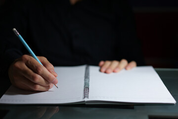 hands writing on notepad in light beam