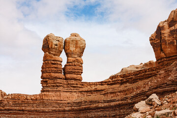 The Twin Rocks of Bluff, is also known as the Navajo Twins, under a blue sky with clouds. The rock...