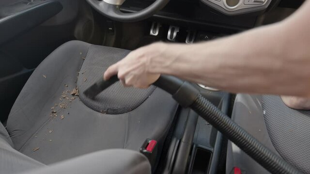 Man cleaning dirty car interior with vacuum cleaner