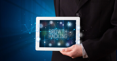Young business person working on tablet and shows the digital sign: GROWTH HACKING