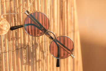 Steampunk sunglasses model with round lenses hanging on a bamboo fence in a summer day closeup. Selective focus 