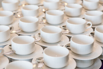 Rows of clean white coffee or tea cups, dish and spoon in a cafeteria or restaurant ready to serve...