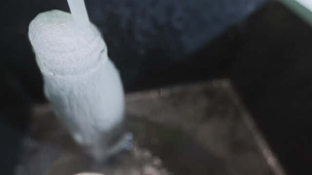 Clean water goes to waste while overfilling bottle