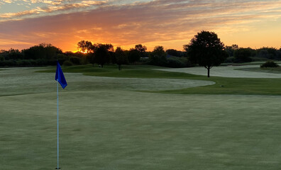 Obraz premium sunrise golf course golf green white blue flag morning dew