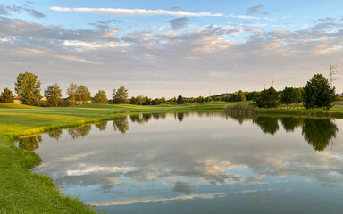 early morning golf course pond reflections green red flag