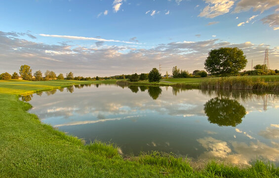 early morning golf course pond reflections green red flag - Powered by Adobe