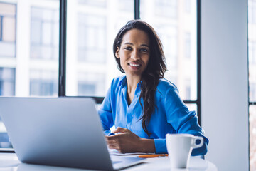 Confident black businesswoman working on laptop at office table