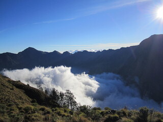 Picturesque volcano mountain filled with clouds. Trekking route to the rocky summit of Mount Rinjani in Lombok Island, Indonesia.
