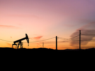 Silhouette of an oil rig or pump industry equipment at sunset.