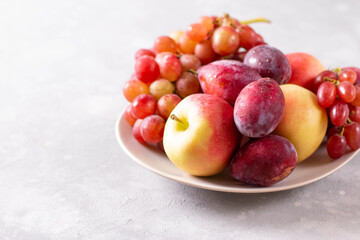 Naklejka na ściany i meble Composition with fruits. Grapes, apples and plums in a plate