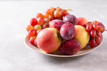 Naklejka na ściany i meble Composition with fruits. Grapes, apples and plums in a plate