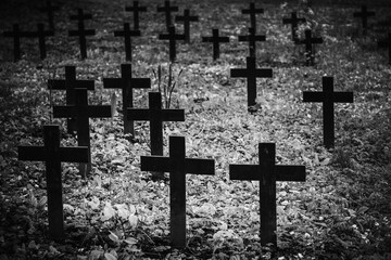 Vintage, retro black and white photo of old graves and crosses in a cemetery. Grainy, noisy, artistic monochrome image. Halloween, all saints concept