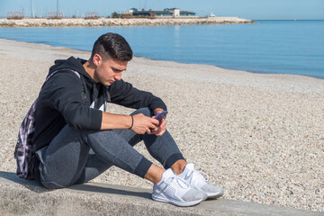 The end of the summer with a boy that play with a smarthphone in a beach