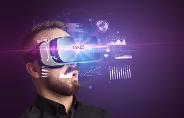 Businessman looking through Virtual Reality glasses with TAXES inscription, new business concept