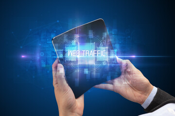 Businessman holding a foldable smartphone with WEB TRAFFIC inscription, new technology concept