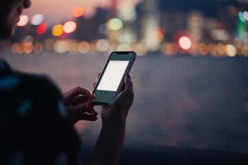 Crop young woman using smartphone with copy space screen on background of blurred night city