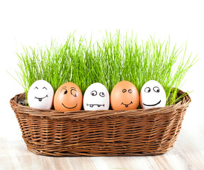 group of Funny crazy smiling eggs in basket with grass. sun bath.