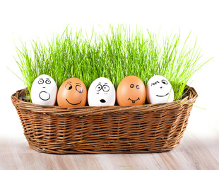 group of Funny crazy smiling eggs in basket with grass. sun bath.