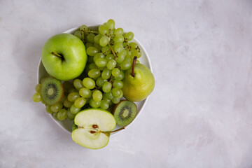 
World Vegetarian Day. Alkaline diet, green fruits on the table with copy space, apples, grapes, kiwi, pears. Vegetarianism. Copy space