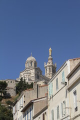 A Marseille, sud de la France, montée vers la basilique Notre-Dame de la Garde, avec des maisons à l'architecture typique de la vieille ville, sur fond de ciel bleu - 377561520