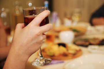 Woman's hand holds a glass of red wine at the table