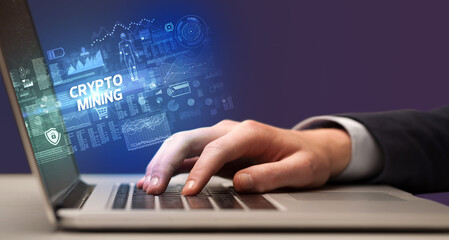 Naklejka na ściany i meble Businessman working on laptop with CRYPTO MINING inscription, cyber technology concept