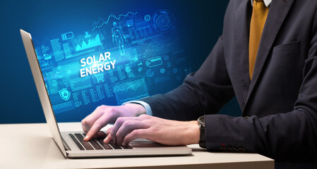 Businessman working on laptop with SOLAR ENERGY inscription, cyber technology concept