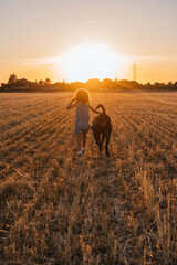 Young girl walking accompanied by her dog in the field