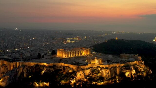 Der beleuchtete Parthenon Tempel auf der Akropolis in Athen, Griechenland, mit Stadtlichtern und und warmen Licht am Abend