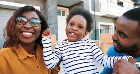 POV of African American young family with small cute girl smiling and talking to camera while...