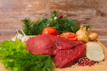 raw beef meat with vegetables on wooden plate.