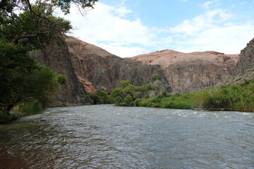 The river flows along a rocky mountain area with vegetation on the shore.