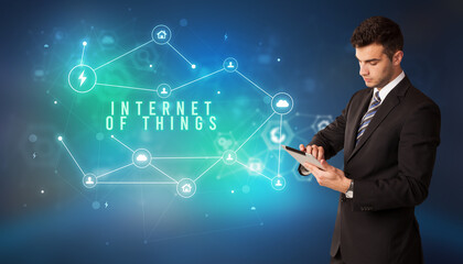 Businessman in front of cloud service icons with INTERNET OF THINGS inscription, modern technology concept