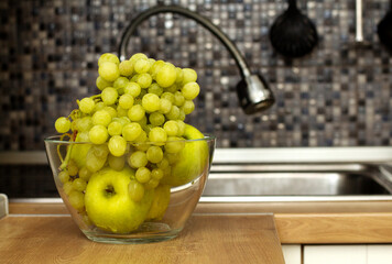 Freshly washed fruit on the kitchen table. Green apples and grapes lie in a glass bowl.