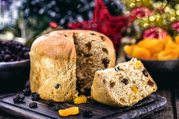 Slice of delicious panettone with candied fruits with blinking blurred Christmas lights, bread with fruits