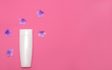 Skin care packaging mockup on a pink background among violet flowers. Flat lay. Cosmetic beauty natural. Face and body treatment. Copy space