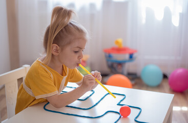 Little girl enjoying game playdough straw maze. Great activity for building oral motor skills at...