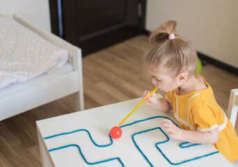 Little girl enjoying game playdough straw maze. Great activity for building oral motor skills at home.