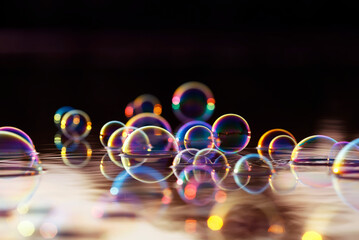 beautiful colorful background with shiny soap bubbles flying over the water and reflected in the...