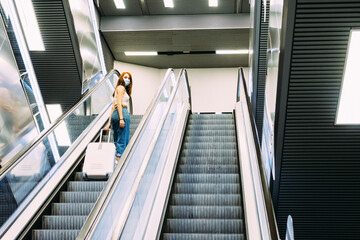 young tourist with face mask uses subway escalator