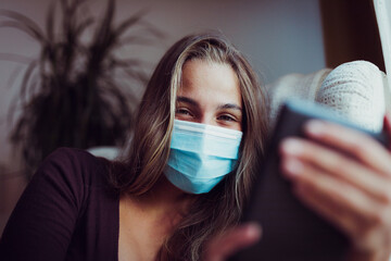 Girl Wearing mask due coronavirus smiles while reading indoors