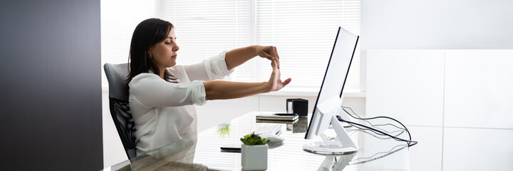 Woman Stretches At Office Desk