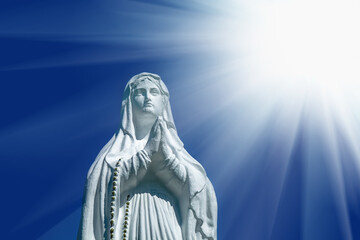 Virgin Mary statue. Vintage sculpture of sad woman in sunlight