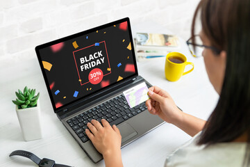 Black friday shopping online concept with discount banner on laptop display. Woman hold credit card concept - obrazy, fototapety, plakaty