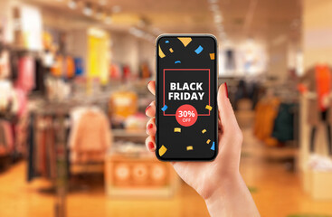 Black friday discount advert on smart phone in woman hand. Store in shopping mall in background concept