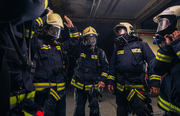 Team of firefighters in the fire department wearing gas masks and uniform