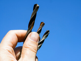 old rusty drill in a man's hand. The craftsman selects the drill.