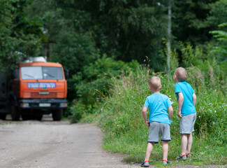 Fototapeta premium Boys from afar watch the work of the concrete mixer