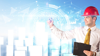 Handsome businessman with helmet drawing DUE DILIGENCE inscription, contruction business concept