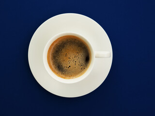 A cup of black coffee on a trendy blue background, top view. Espresso or americano. Cafe and bar, barista art concept. Minimalism.
